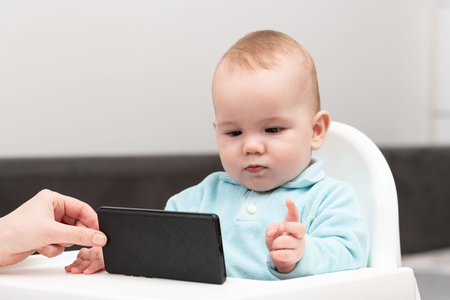 Baby Child In Chair And Playing With Mobile Phone