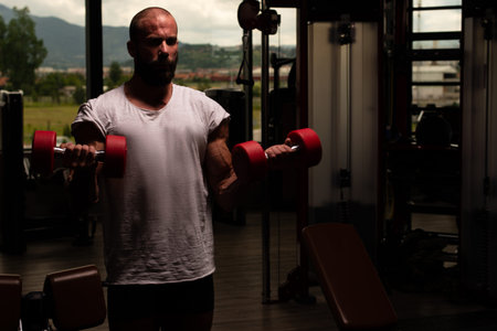 Healthy Man Working Out Biceps In A Dark Gym - Dumbbell Concentration Curls
