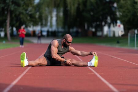 Young Athlete Man Relax and Strech Ready for Run at Athletics Race Track on Stadiumの写真素材