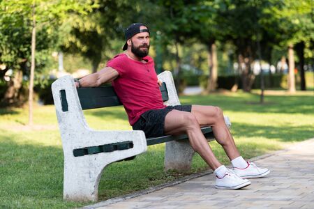 Portrait of a Happy Young Man Resting in a Park Bench After Doing Some Jogging Outdoorsの写真素材