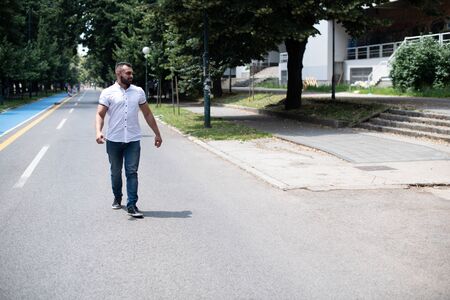 Portrait of a Confident and Successful Young Man With White T-Shirt Walking Outside in Parkの写真素材
