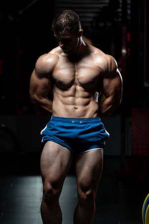 Portrait Of A Young Physically Fit Man Showing His Well Trained Body - Muscular Athletic Bodybuilder Fitness Model Posing After Exercisesの写真素材