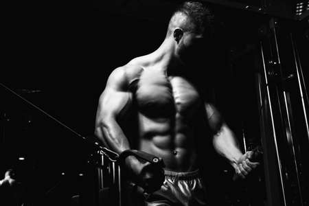 Handsome Muscular Fitness Bodybuilder Doing Heavy Weight Exercise For Chest On Machine With Cable In The Gymの写真素材