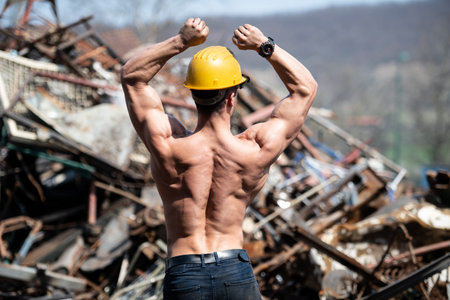 Portrait of a Young Physically Fit Man Standing in Industrial Junk Yard Showing His Well Trained...