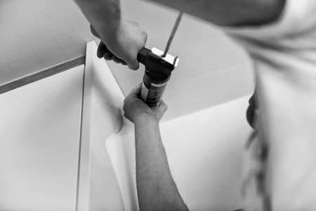 Construction Worker Use Gun Silicone Tube for Repairing and Installing Ceiling in Houseの写真素材