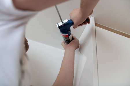 Construction Worker Use Gun Silicone Tube for Repairing and Installing Ceiling in Houseの写真素材