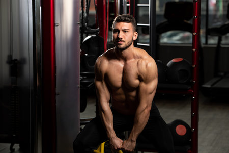 Man Working Out With Kettle Bell In A Dark Gym - Bodybuilder Doing Heavy Weight Exercise With Kettle-bellの写真素材
