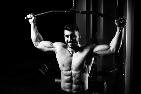 Handsome Bodybuilder Doing Heavy Weight Exercise For Back On Machine