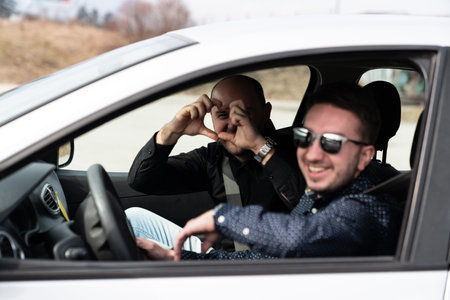 Young Man Getting a Driving Lesson in the Car and Driver Making Sign Heart by Fingers