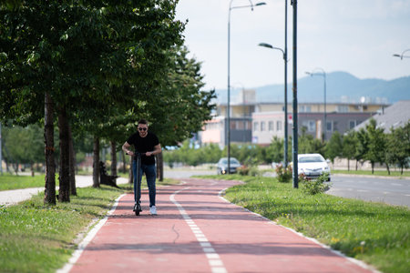 Young Man Riding on Scooter Along the Street in the City