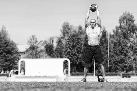 Man Working Out With Kettle Bell Outdoors - Bodybuilder Doing Heavy Weight Exercise With Kettle-bellの写真素材