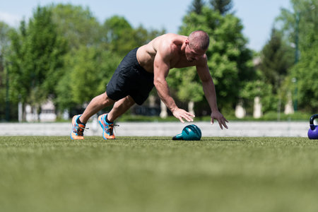 Healthy Man Athlete Doing Pushups Workout With Kettle Bell Outdoor - Kettle-bell Exerciseの写真素材
