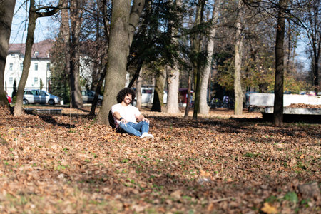 Portrait of a Young Man Afro Hair Resting in Forest Outside During Autumnの写真素材