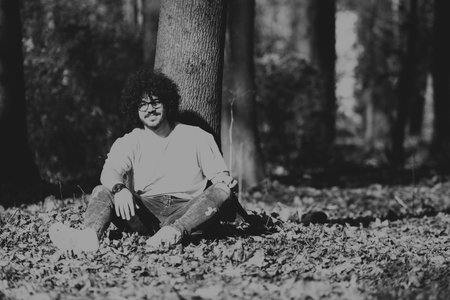Portrait of a Young Man Afro Hair Resting in Forest Outside During Autumn
