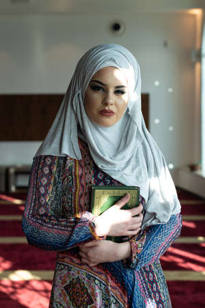 Young Traditional Muslim Woman Taking Quran in the Mosqueの写真素材