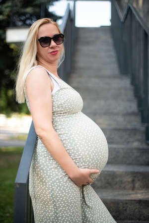 Stomach of the Pregnant Woman in a Summer Dress on the Stairsの写真素材