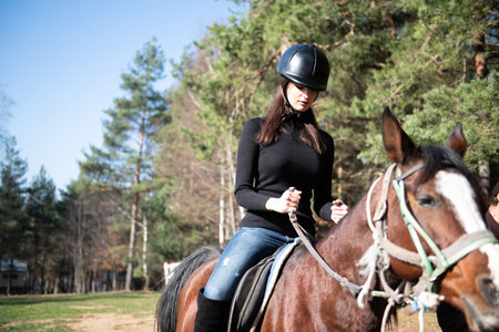Young Woman Jockey Riding Brown Horse Strolling Across Field