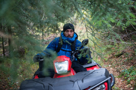 Male Rescuer in Protective Uniform on a Quad Bike Observe the Woods to Search and Save Missing...