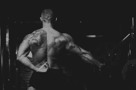 Man Standing Strong In The Gym And Flexing Muscles - Muscular Athletic Bodybuilder Fitness Model Posing After Exercisesの写真素材