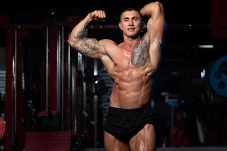 Portrait Of A Physically Fit Man Showing His Well Trained Body - Muscular Athletic Bodybuilder Fitness Model Posing After Exercisesの写真素材