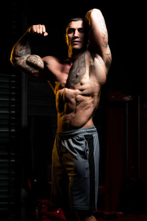 Man Standing Strong In The Gym And Flexing Muscles - Muscular Athletic Bodybuilder Fitness Model Posing After Exercisesの写真素材