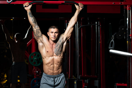 Bodybuilder Performing Hanging Leg Raises Exercise - One Of The Most Effective Ab Exercises