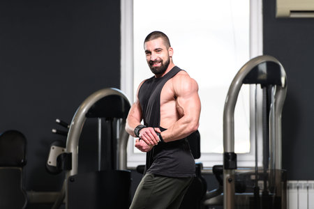 Young Man Standing Strong In The Gym And Flexing Muscles - Muscular Athletic Bodybuilder Fitness...