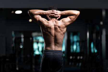 Young Man Standing Strong In The Gym And Flexing Muscles - Muscular Athletic Bodybuilder Fitness Model Posing After Exercisesの写真素材