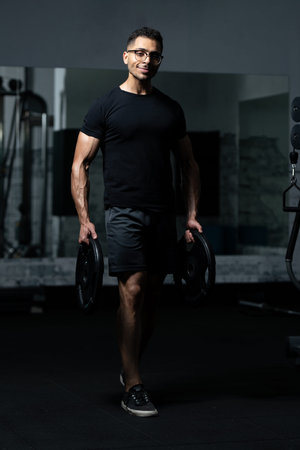 African Man Standing Strong in the Gym and Holding Weights in Hand