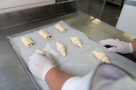 Young Pastry Chef Making Some Croissant in the Bakery Cooking Process Before Going to the Ovenの写真素材
