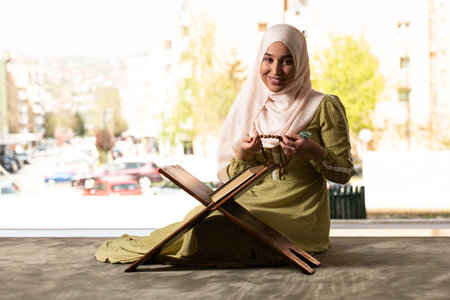 Beautiful Muslim Woman in Hijab Dress Sitting in Mosque and Praying With Quran