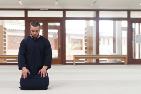 Young Muslim Man Making Traditional Prayer To God While Wearing A Traditional Cap Dishdashaの写真素材