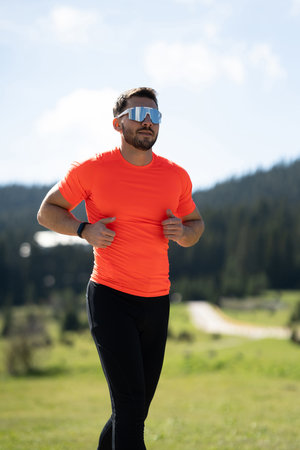 Athlete Jogging On A Dedicated Running Path With Stunning Natural Views Of Grass, Forests, And Distant Mountainsの写真素材