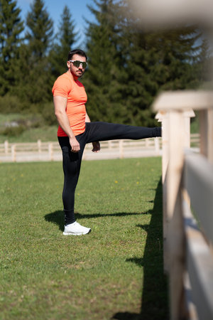 Man Performs Outdoor Stretching For Flexibility And Strength Before Trainingの写真素材