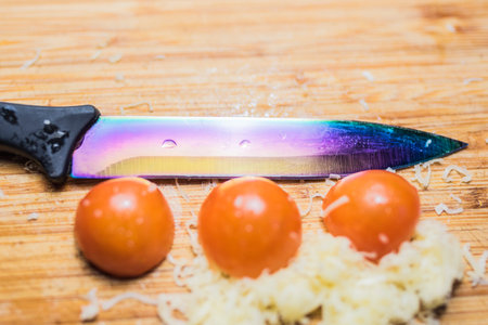 colored knife, cherry tomatoes and cheese and on a cutting boardの写真素材