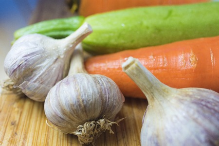 zucchini and carrots and 3 head of garlic on a cutting boardの写真素材