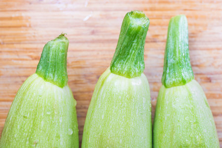 Three zucchini on a wooden kitchen board