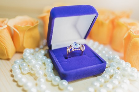 Gold ring with a blue gem in a gift box on pearlsの写真素材