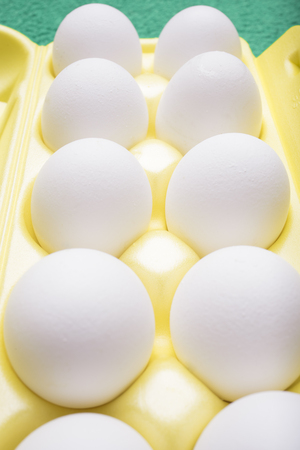 Ten white chicken eggs lie in a yellow tray, a vertical frameの写真素材