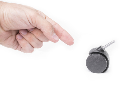 Hand points to a plastic furniture wheel isolated on a white backgroundの写真素材