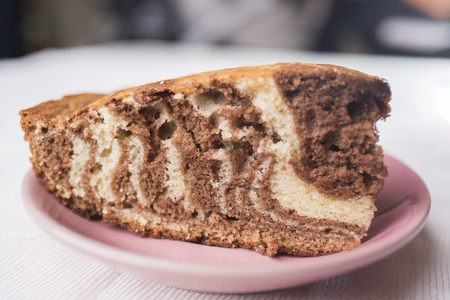 Piece of zebra pie on a saucer of mauve-colored on a white lace background, close-upの写真素材