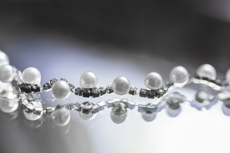 Silver necklace with white pearls lies on a mirror backgroundの写真素材