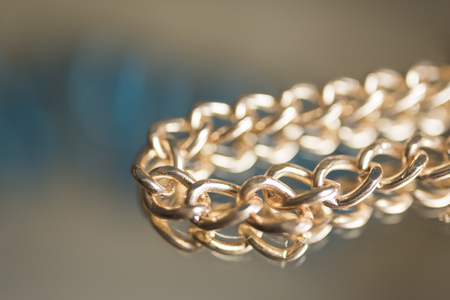 Gold chain close-up lies on a mirror blurred backgroundの写真素材