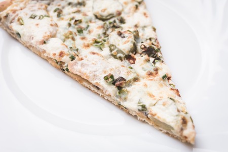 Piece of pizza closeup on a white plateの写真素材