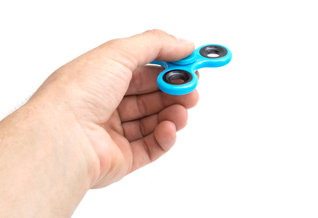 Hand holding a twist blue spinner stress relieving toy isolated on white backgroundの写真素材