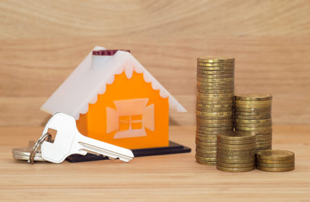 A house with keys and coins stack on wooden backgroundの写真素材