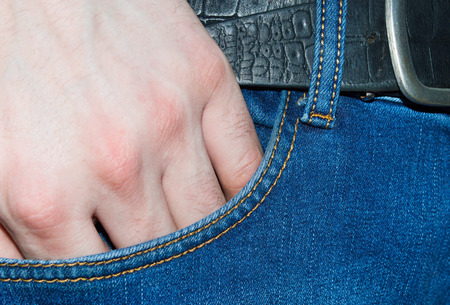 A hand in blue jeans pocket fabric textile close up texture background.の写真素材