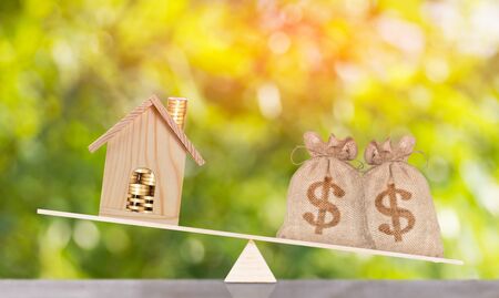 home and money bag put on the balance scales Saving for buy a new home or loan for plan business investment concept.の写真素材