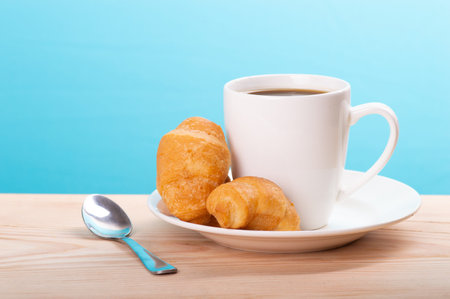 delicious coffee with croissant on wooden table and blue backgroundの写真素材
