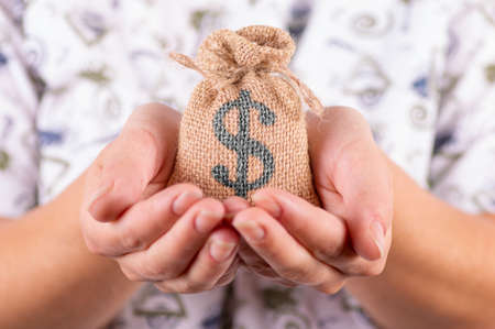 woman hands hold sack bag with dollar sign close up.の写真素材